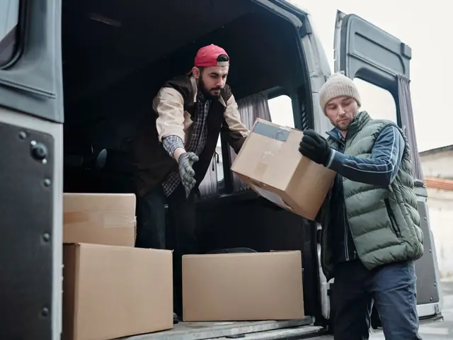 Two movers unloading boxes from a moving van